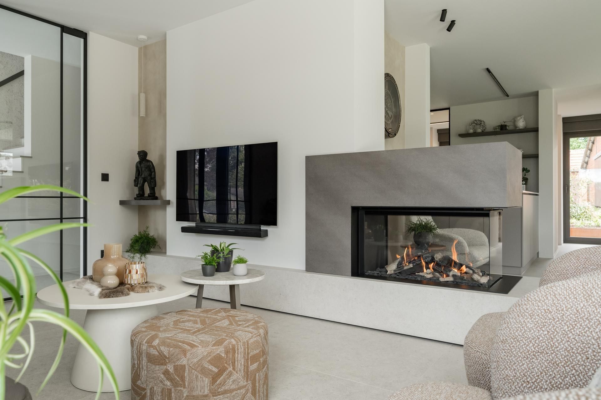 Sfeervolle woonkamer met moderne haard en zwevend tv-meubel, verlevendigd door glazen deuren en stijlvolle planten.